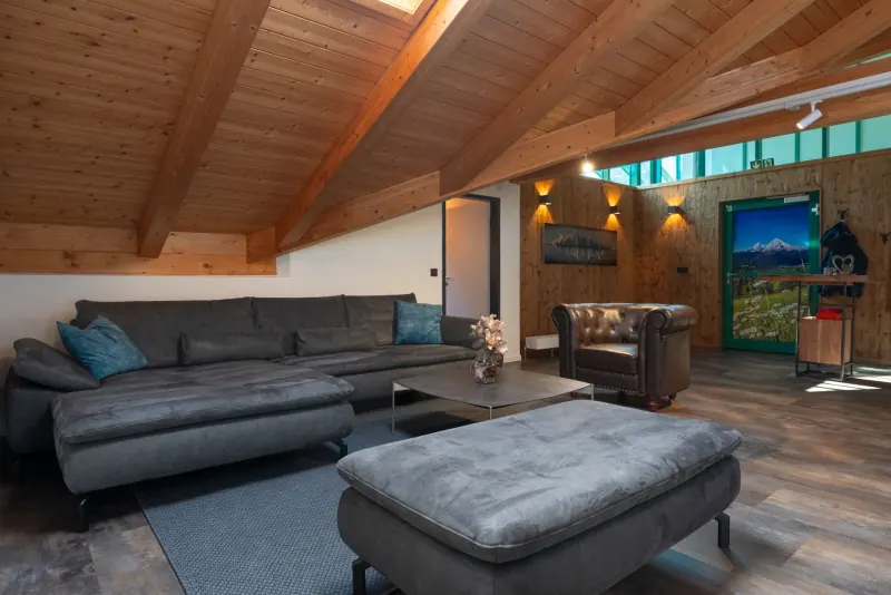 Ferienwohnung Untersbergblick: Wohnbereich mit Ledersofa unter Holzbalken