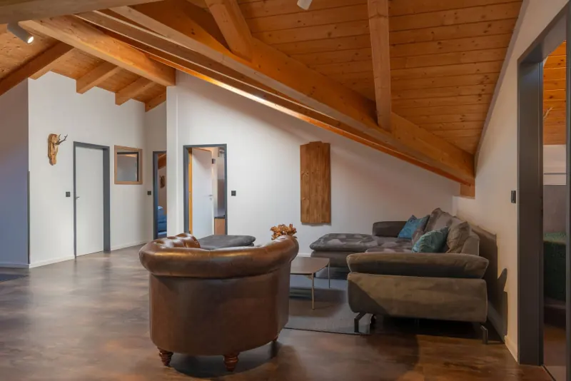 Ferienwohnung Untersbergblick: Wohnbereich mit Ledersessel unter der Holzdecke