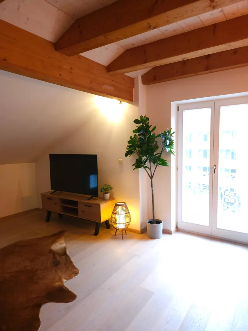 Ferienwohnung Zwieselblick: Wohnzimmer mit Holzbalken und Balkontür